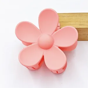 Detail view of a matte pink five-petal flower hair claw clip with elegant texture