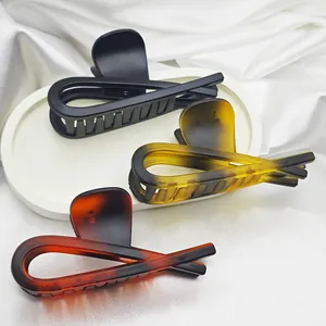 Detail view of three large matte hair claw clips in black and tortoiseshell patterns.
