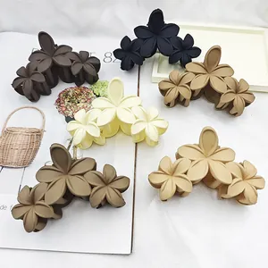 Variety of large matte plumeria flower hair claw clips in assorted neutral earthy tones.