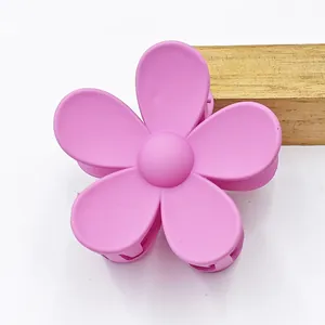 Close-up shot of a matte pink five-petal flower hair claw clip on a clean white surface