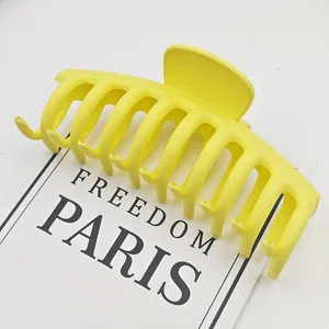 Primer plano macro de una pinza para el pelo de tiburón amarillo mate sobre tarjeta blanca
