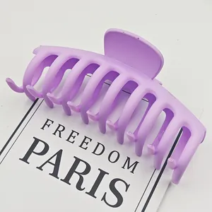 Primer plano detallado de una pinza grande para el pelo morado mate sobre tarjeta blanca