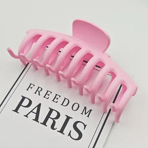 Primer plano de una pinza para el cabello rosa mate grande con diseño de dientes cruzados.