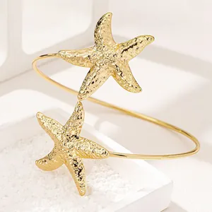 Dettaglio macro di un bracciale da braccio dorato con stelle marine per look da spiaggia