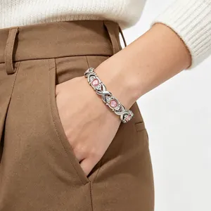 Detailed view of a silver-tone cross link bracelet with pink stones worn on a wrist