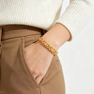 Close-up of a gold-plated magnetic bracelet with pink stones worn on a wrist.
