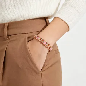 Close-up detail showing a rose gold magnetic bracelet with pink stones on a wrist