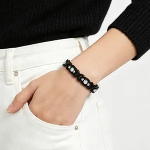 Close-up of a black detachable cross magnetic bracelet with rhinestones on a wrist