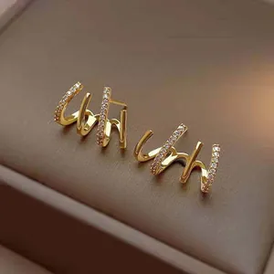 Detail macro view of elegant gold claw earrings pavé-set with brilliant white crystals
