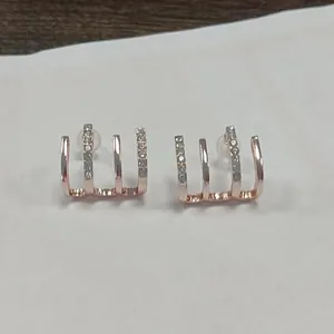 Close-up detail of rose gold claw-shaped earrings with sparkly rhinestone accents