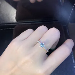 Détail macro montrant une bague minimaliste en argent avec un zircon étincelant.