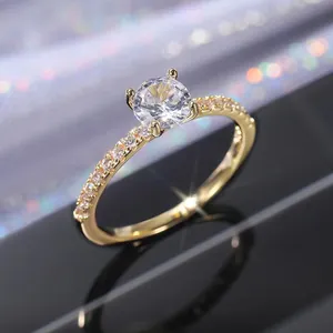 Gros plan d'une bague en or avec zircon rond et pavé de pierres sur fond noir réfléchissant