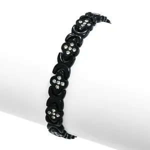 Dettaglio ravvicinato di un bracciale magnetico nero con quadrifogli e strass brillanti