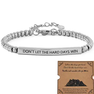 Detail view of an inspirational stainless steel bar bracelet with motivational quote card