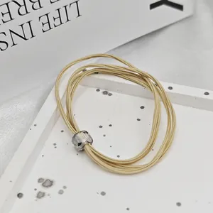 Gros plan d'un élastique à cheveux beige haute élasticité avec une perle facettée.