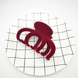 Primer plano de una pinza para el cabello de terciopelo burdeos flocado sobre cuadrícula.
