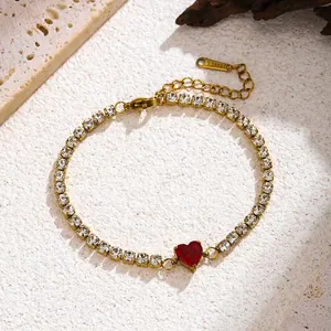 Close-up of a gold heart tennis bracelet with clear rhinestones and a red heart gem