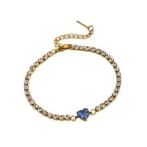 Close-up of a gold tennis bracelet featuring a central blue heart-shaped zircon stone