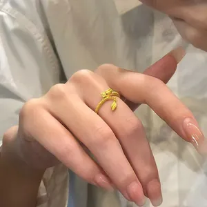 Close-up of a gold-colored dragon zodiac ring with a dangling charm on a model's finger