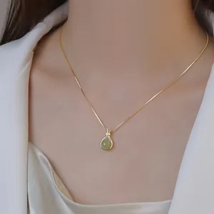 Elegant gold chain necklace featuring a green jade purse-shaped pendant on a model's neck