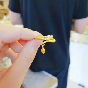 Close-up of a gold-colored dragon ring featuring a delicate leaf dangle and textured band.