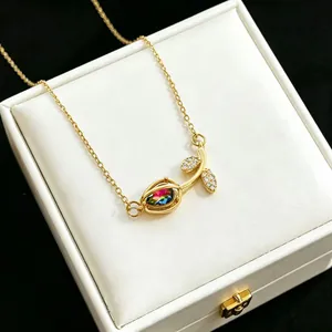 Macro detail of a gold tulip necklace featuring a rainbow crystal and pavé leaves.