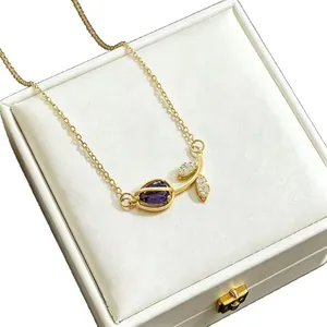 Macro view of gold-tone tulip pendant necklace with purple stone in a white gift box