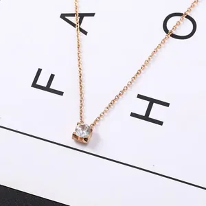 Primo piano di una collana minimalista in oro rosa con cristallo rotondo a 4 griffe