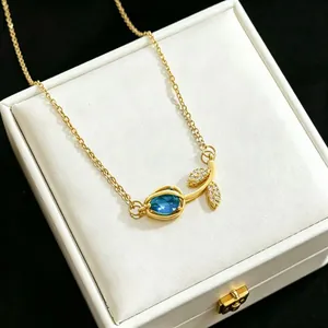 Detailed macro view of elegant gold tulip necklace with blue crystal pendant in a box