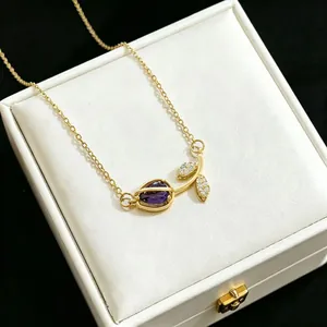 Detailed macro view of a gold tulip necklace with a purple stone and pavé leaves