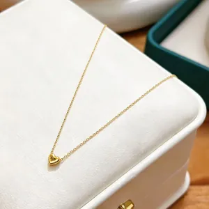 Detailed macro view of a gold stainless steel heart pendant necklace on a white jewelry box
