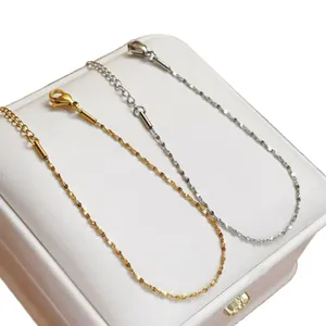 Set of delicate gold and silver titanium steel necklaces displayed on a white jewelry box.