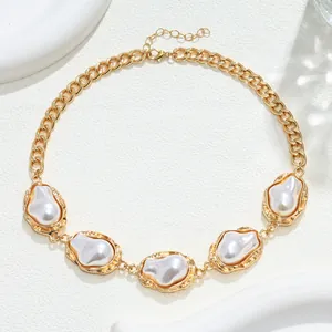 Primo piano di una collana a catena dorata con perle barocche e montature dorate martellate
