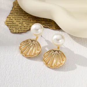 Detailed view of gold shell earrings with elegant white pearls.