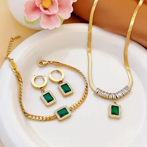 Macro detail of elegant gold-plated jewelry set with emerald green rectangle zircons