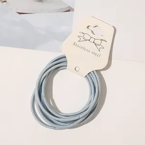 Close-up of light blue elastic hair ties bundled on a bow-decorated cardboard tag
