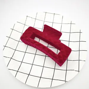 Primer plano de la textura acolchada en una pinza de pelo de terciopelo burdeos flocado