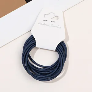 Close-up macro view of thin dark blue elastic hair ties on white fashion jewelry display card.