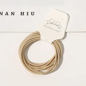 Macro detail of beige high-elastic hair ties presented on a clean white cardboard tag