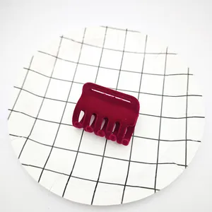 Vista detallada de una pinza para el cabello de terciopelo flocado rojo vino en plato
