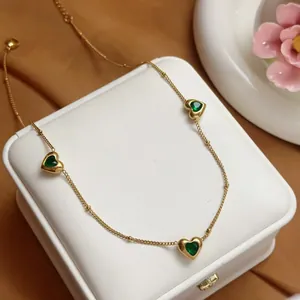 Detailopname van een elegante gouden roestvrijstalen ketting met groene hartstenen