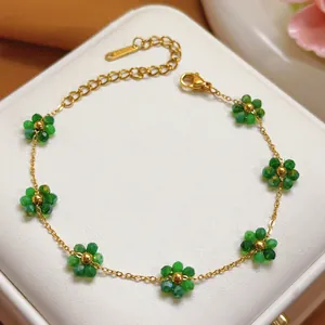 Close-up of a dainty gold stainless steel bracelet with green crystal flower charms