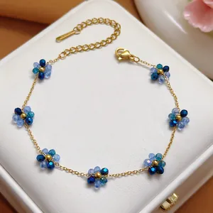 Detailed macro view of a gold stainless steel chain adorned with blue crystal flower charms
