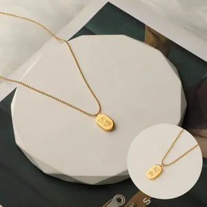 Detailaufnahme einer vergoldeten Titaneisenkette mit einem gravierten Glücksanhänger
