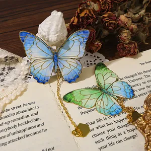 Exquisite vintage butterfly metal bookmark with gold chain set on open book pages.