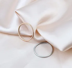 Detailed view of minimalist gold and silver titanium steel thin rings on soft silk fabric