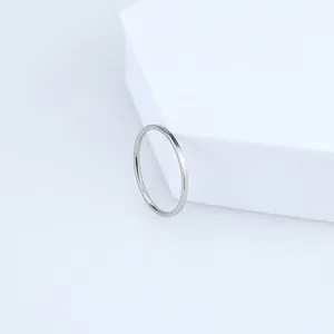 Close-up detail view of a minimalist silver titanium steel slim band ring on a white block