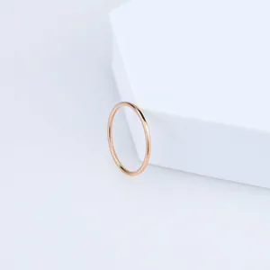 Close-up of a minimalist rose gold titanium steel slim ring resting on white geometric block