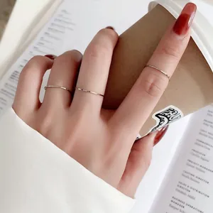 Close-up of three ultra-thin silver titanium steel minimalist rings on fingers holding a cup
