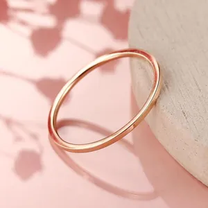 Close-up macro view of a minimalist rose gold titanium steel thin ring resting on wood